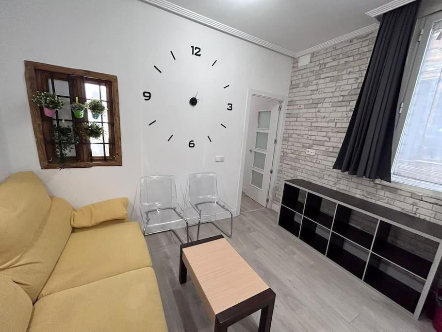 ein Wohnzimmer mit einem Sofa und einer Uhr an der Wand in der Unterkunft Nice flat in Gran Via CB-GRAC-18B in Madrid
