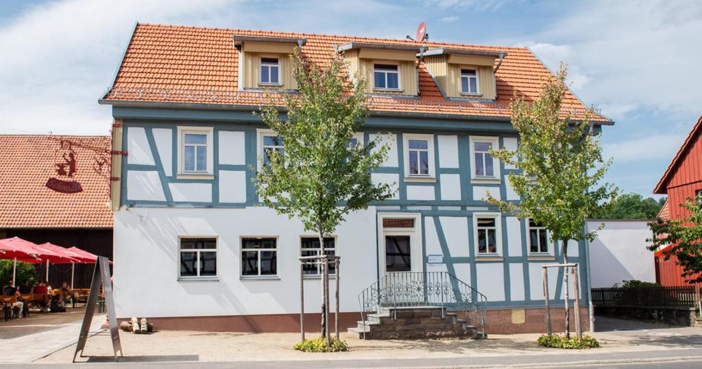 una casa azul y blanca con árboles delante en Schmidts, en Herbstein