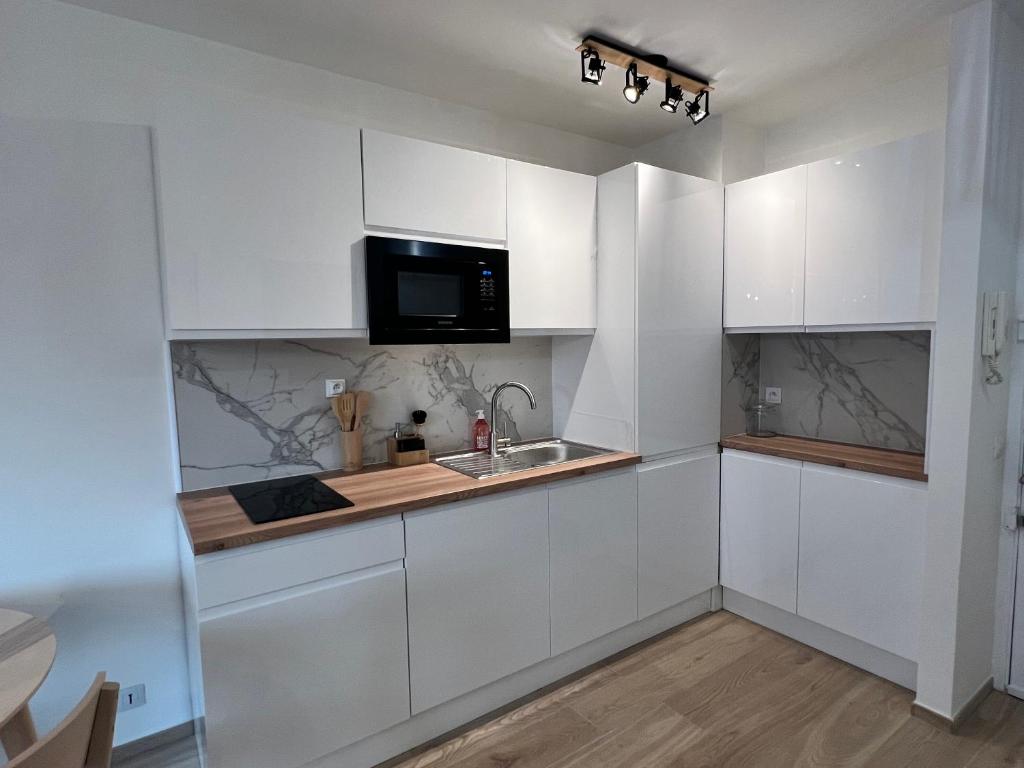une cuisine blanche avec un évier et un micro-ondes dans l'établissement Studio neuf et central, à Antibes