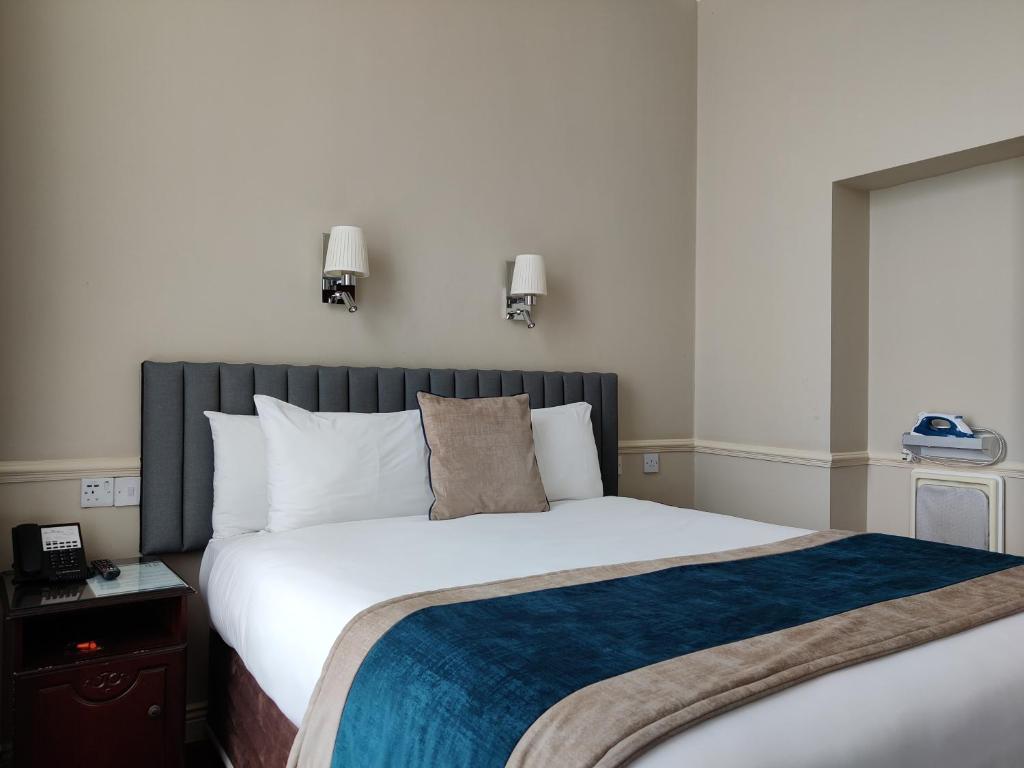 a bedroom with a large white bed with a blue blanket at Harcourt Hotel in Dublin