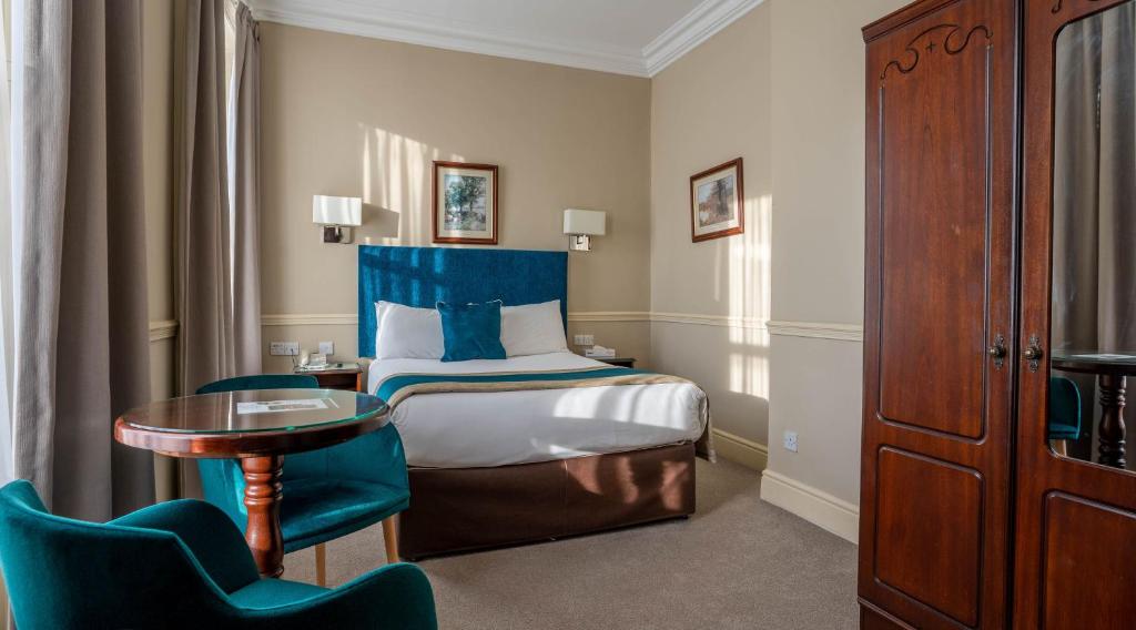 a hotel room with a bed and a table and chairs at Harcourt Hotel in Dublin