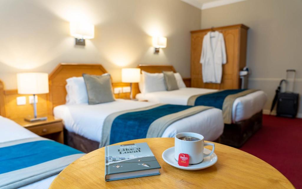 a hotel room with two beds and a cup of coffee on a table at Harcourt Hotel in Dublin