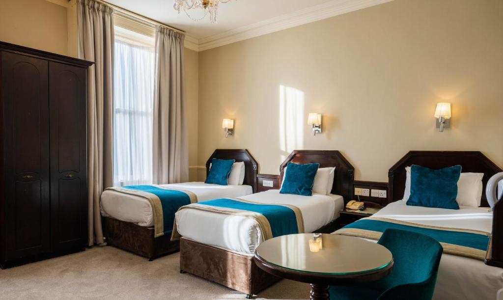 a hotel room with two beds and a table at Harcourt Hotel in Dublin