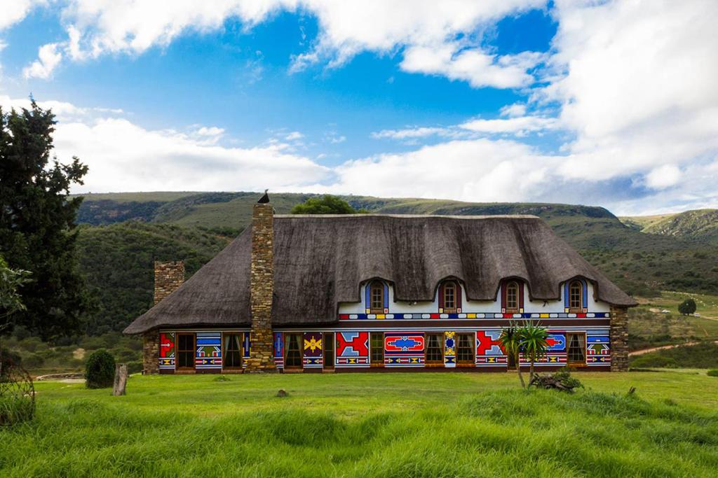 a house with a thatched roof in a field at Addo Bush Palace in Addo