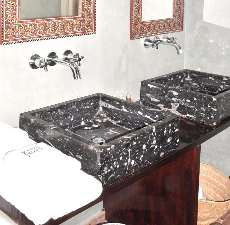 a bathroom with two black sinks and two faucets at Hotel Blanco Riad in Tetouan