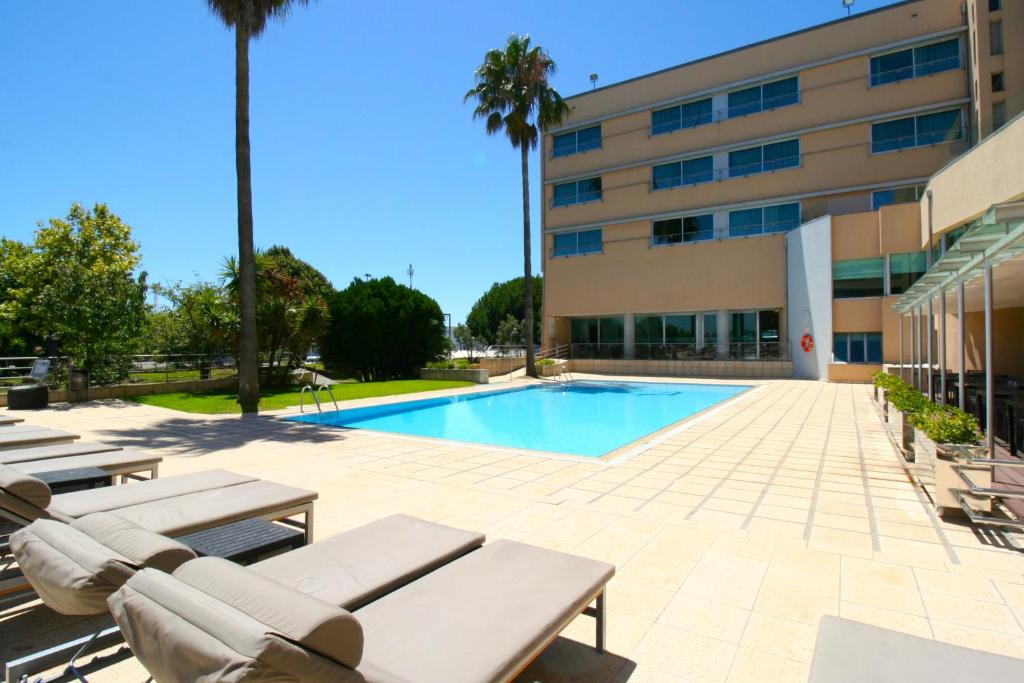 a swimming pool with lounge chairs and a building at TRYP by Wyndham Porto Expo Hotel in Leça da Palmeira