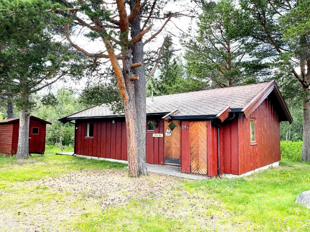 ein roter Schuppen auf einem Feld mit Bäumen in der Unterkunft Ådnebu by Norgesbooking - cabin with 3 bedrooms in Geilo