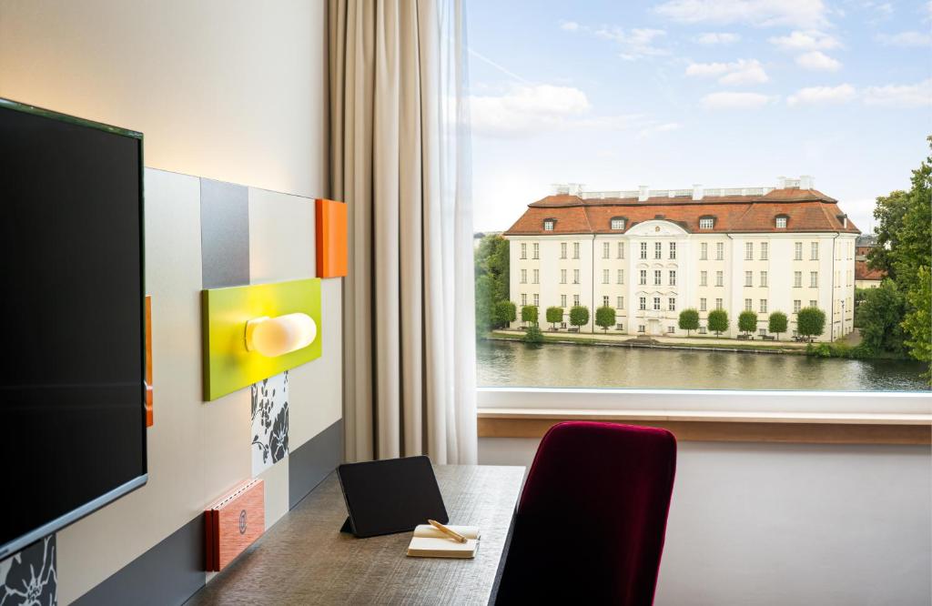 a room with a table and a window with a building at HOTEL BERLIN KÖPENICK by Leonardo Hotels in Berlin
