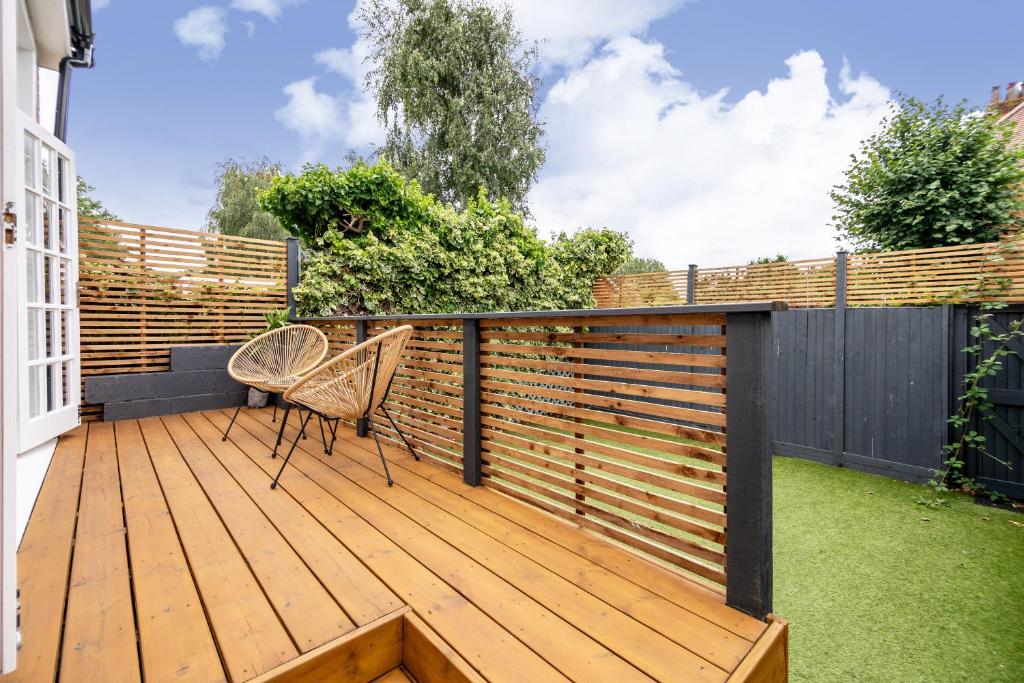 a deck with a fence and two chairs on it at Spacious 3 BR house wParking & Garden, Wimbledon in New Malden