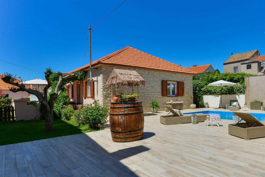 a house with a barrel in a yard with a pool at Seaview Holiday Home GATSBY in Petrcane