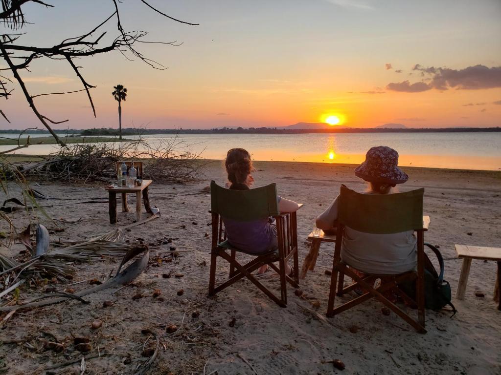 Kwa Mhinda的住宿－Makubi Safari Camp by Isyankisu，两人坐在沙滩椅上,欣赏日落