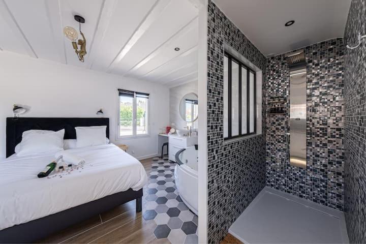 a bedroom with a bed and a bathroom with a shower at Maison SPA DISNEY in Lagny