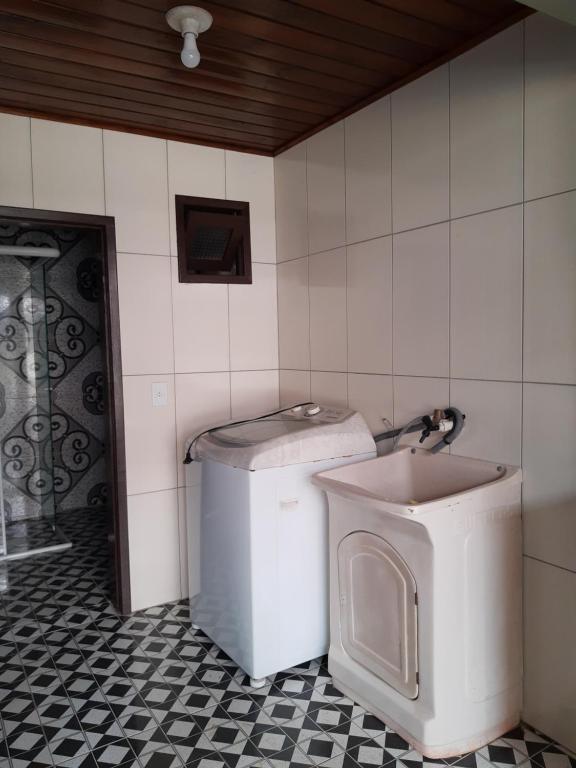 a bathroom with a washing machine and a toilet at Apartamento com pátio e anexo exclusivo in Torres