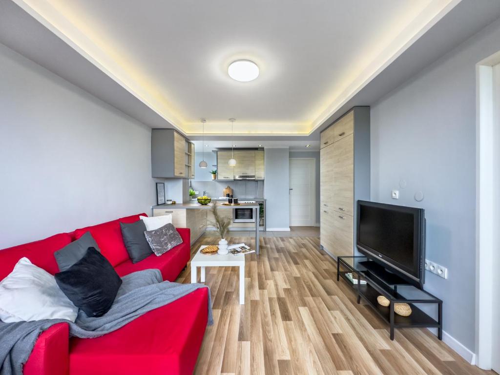 ein Wohnzimmer mit einem roten Sofa und einem TV in der Unterkunft Apartament z widokiem na panoramę miasta in Krakau