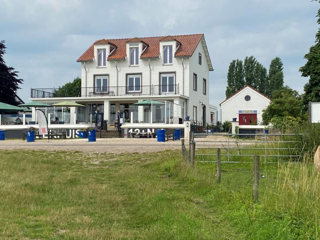una gran casa blanca con una valla delante en Het Veerhuis, en Oeffelt