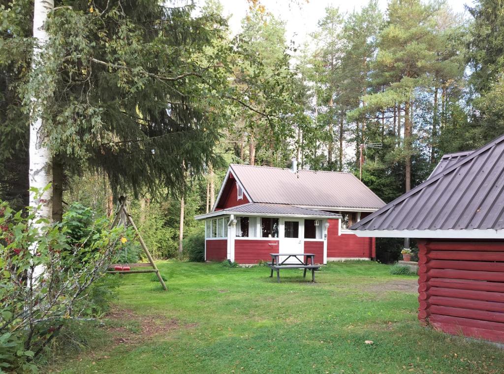 ein rotes und weißes Haus mit einem Picknicktisch im Hof in der Unterkunft Punatulkku in Kalajoki