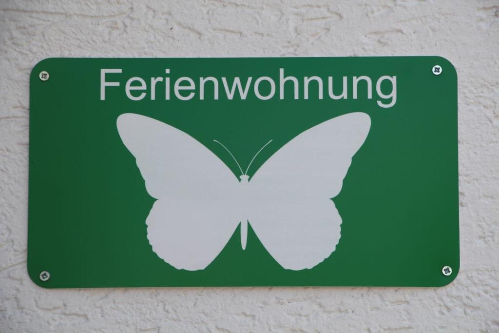 una señal verde con una mariposa blanca en la pared en Ferienwohnung Schmetterling, en Trendelburg
