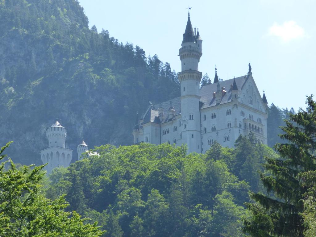 ein Schloss auf einem Hügel mit Bäumen in der Unterkunft Casa Fuessen in Füssen