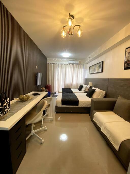 um quarto de hotel com duas camas, uma secretária e um sofá em Condo Suite/Apartment Pasay SM MOA - Stay Cozy & Boujee em Manila