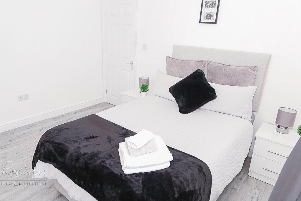 1 dormitorio con cama blanca y almohada negra en City Village en Bickley