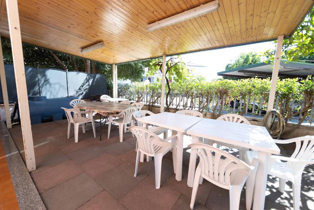un patio con mesas blancas y sillas blancas en Appartanvilla con giardino terrazzo e parcheggio privato, en Mascali