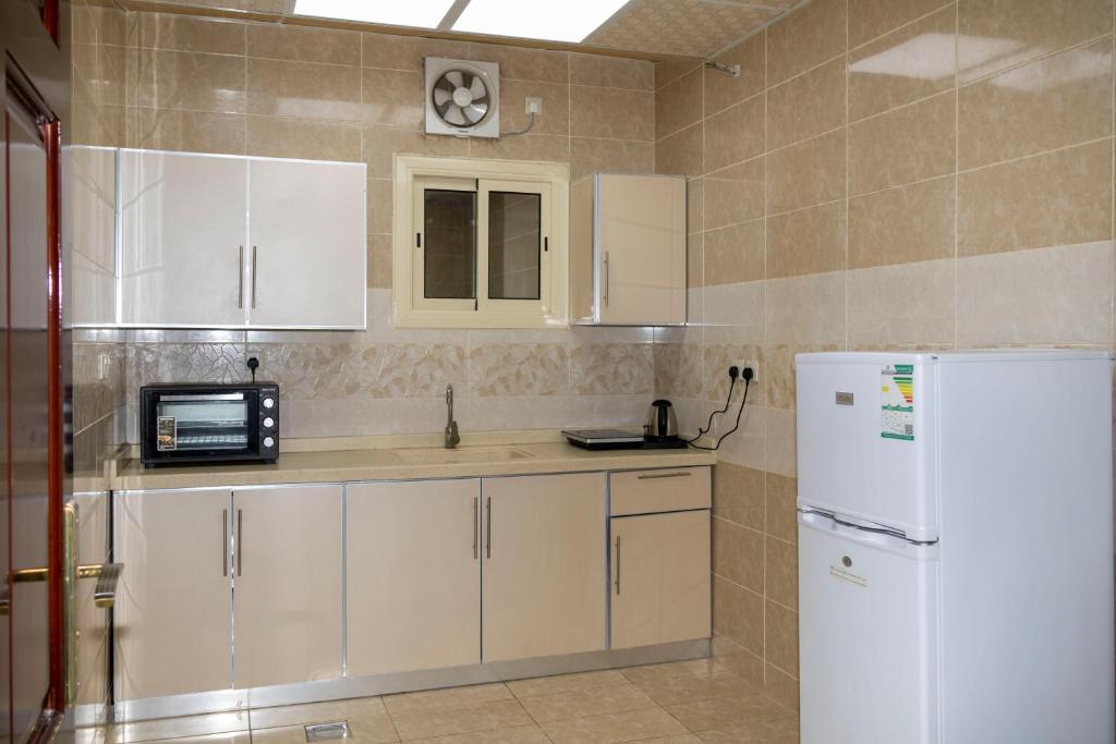 a kitchen with white cabinets and a white refrigerator at غزالي للوحدات السكنية in Al Madinah