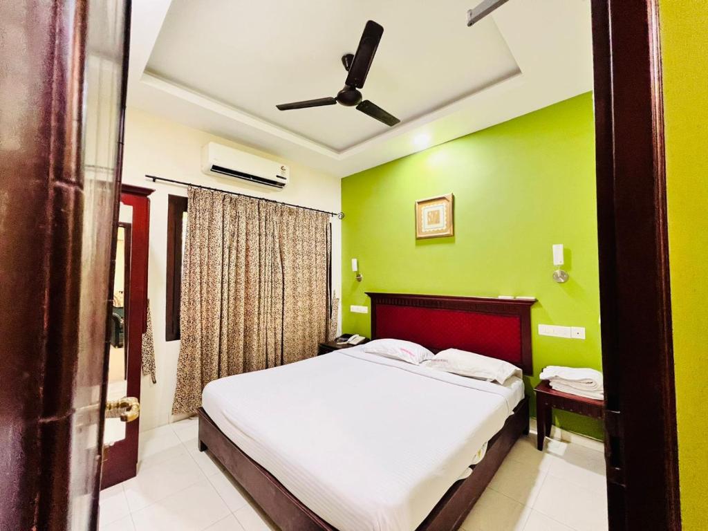 1 dormitorio con cama y pared verde en Guruvayoor Resort, en Guruvāyūr