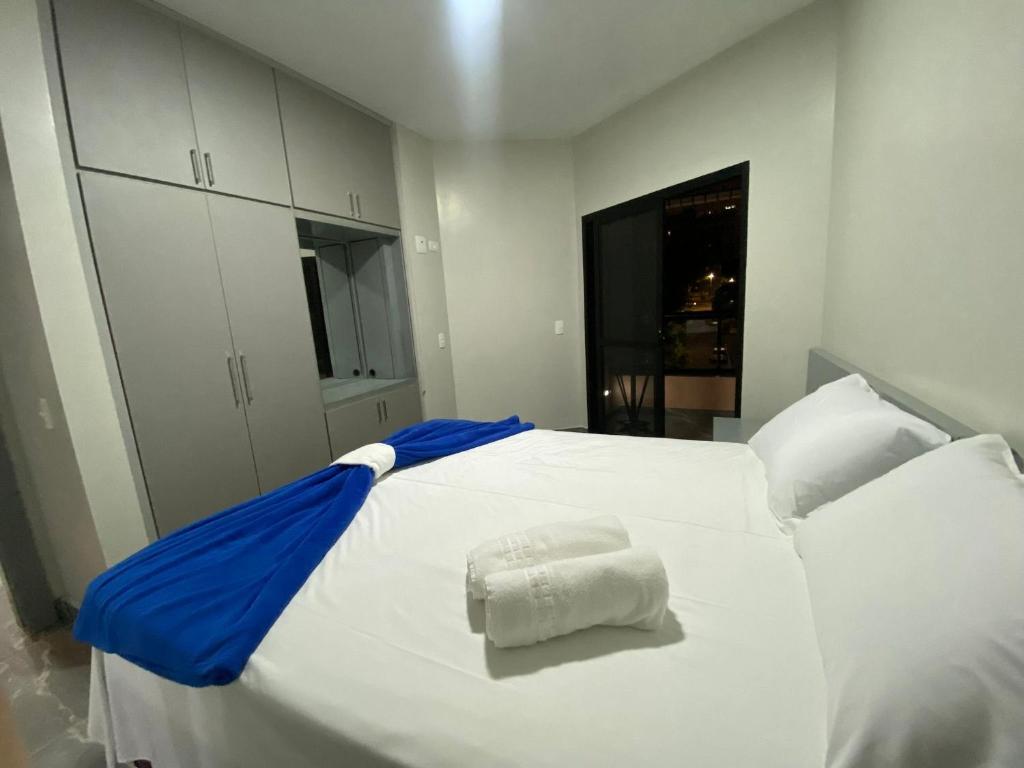 a large white bed with a blue blanket on it at Flat no coração de brasília in Brasilia