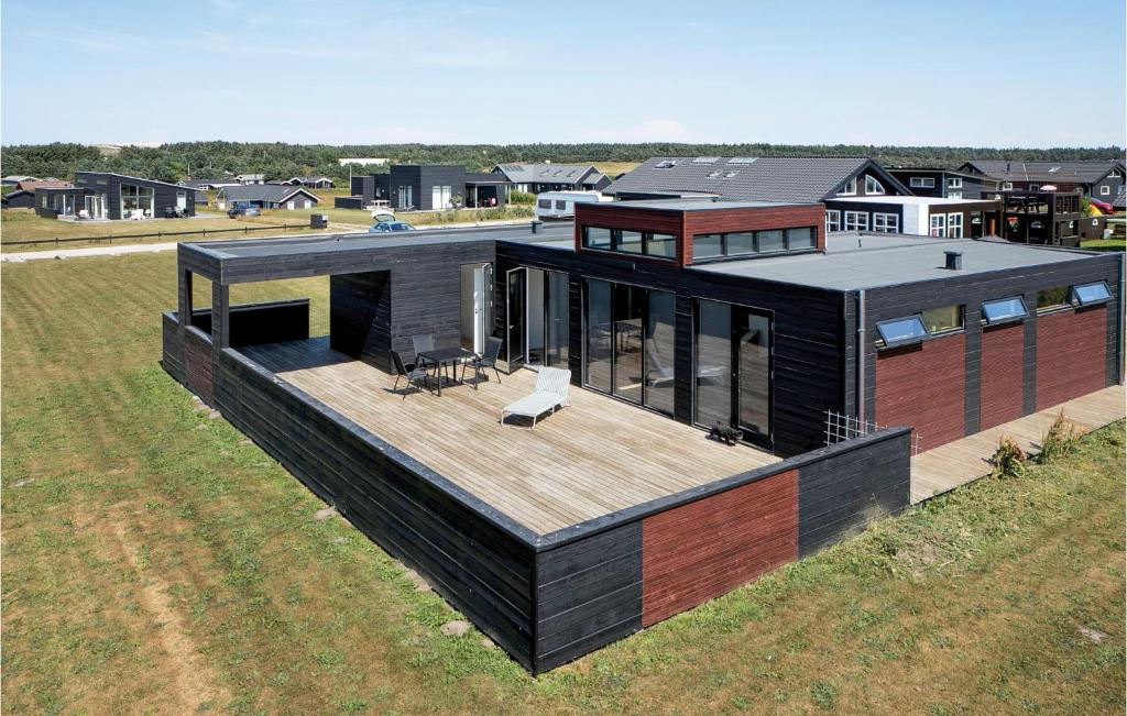 a black house with a deck on top of a field at Three-Bedroom Holiday Home In Lokken in Løkken