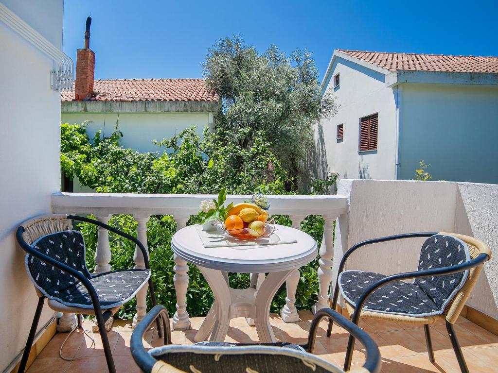 - une table et des chaises sur un balcon avec un bol de fruits dans l'établissement Rooms Garden, à Petrovac na Moru