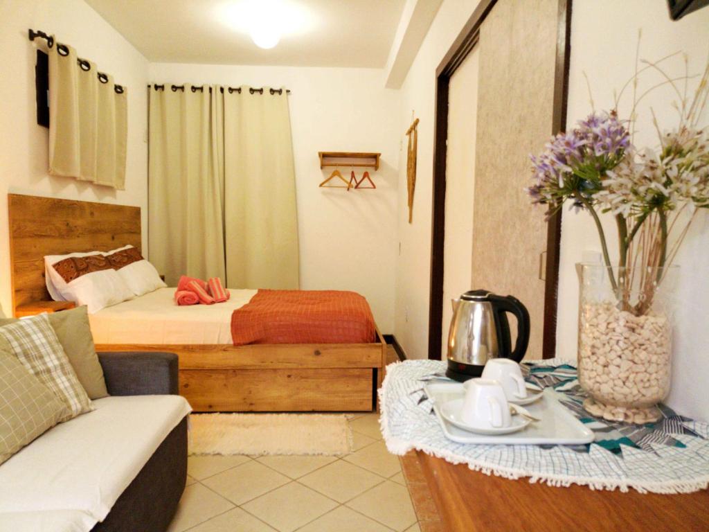 Habitación de hotel con cama, sofá y mesa en Solar das Pétalas Guest House, en Florianópolis