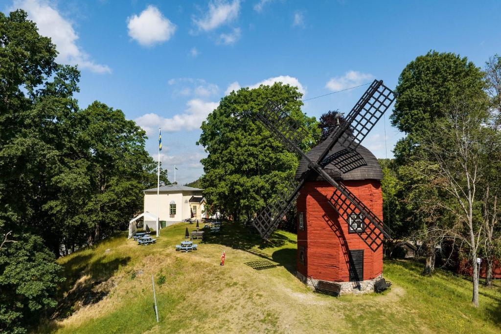 eine Windmühle auf einem Hügel mit einem Haus in der Unterkunft Korskullens Stugor in Söderköping