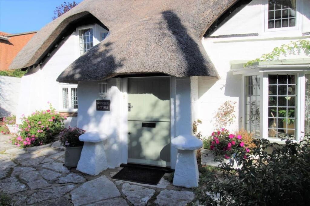 a white house with a thatch roof at Smugglers Cottage in Barton on Sea