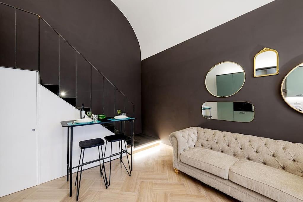 a living room with a couch and a table and mirrors at Loft Corso Cavour in Perugia