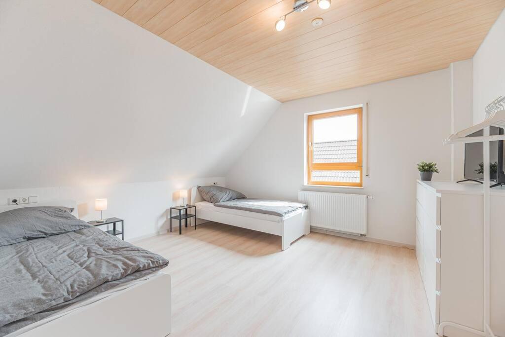 a white bedroom with a bed and a window at G03 große 8er Maisonette Wohnung - ideal für Teams und Monteure - Self Check-In in Gäufelden