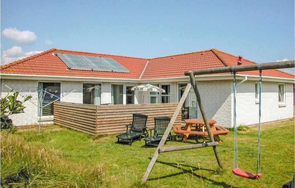 a house with a swing and a house with a solar roof at Beautiful Home In Blokhus With Sauna, Wifi And Indoor Swimming Pool in Blokhus