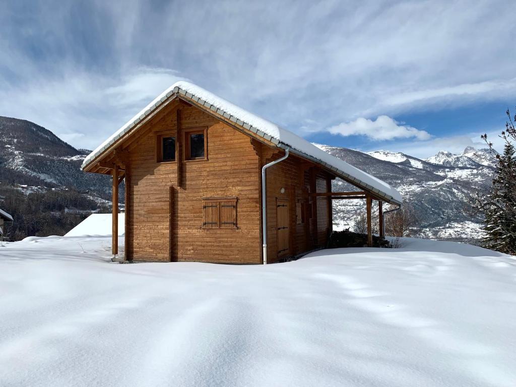 eine Holzhütte im Schnee in den Bergen in der Unterkunft Chalet de la Rua, Risoul Village in Risoul