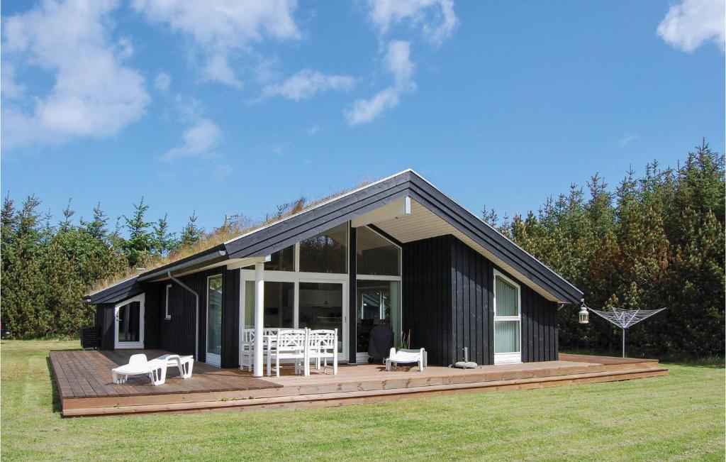 una casa nera con una terrazza in legno in un campo di Beautiful Home In Pandrup With Wifi a Rødhus