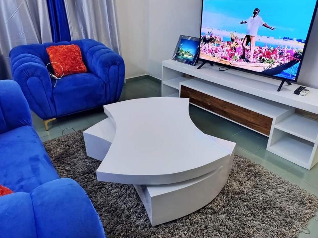 sala de estar con sofá azul y TV en Meublés en Cotonú