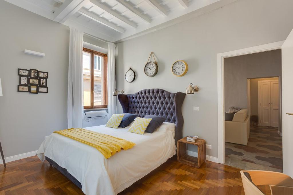 1 dormitorio con 1 cama grande y reloj en la pared en RomExperience Borgo Pio en Roma