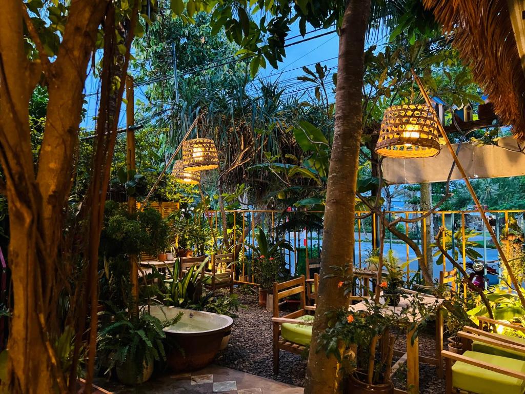 a garden with palm trees and chairs and chandeliers at Uyen's House in Con Dao