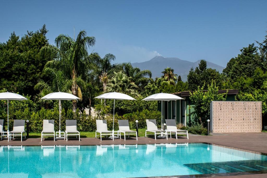a swimming pool with chairs and umbrellas at Virdamuri - Etna Country Resort in Giarre