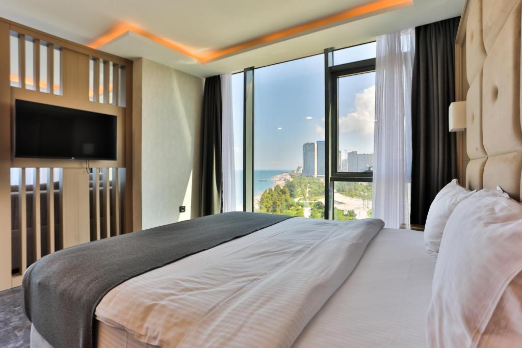 a bedroom with a large bed with a large window at Batumi View Luxury in Batumi