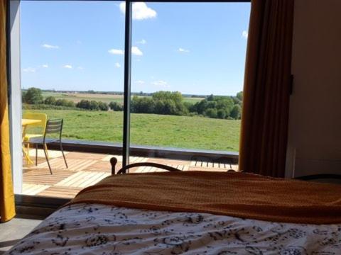 Schlafzimmer mit einem Bett und einem großen Glasfenster in der Unterkunft Le pré en bulles in Lespesses