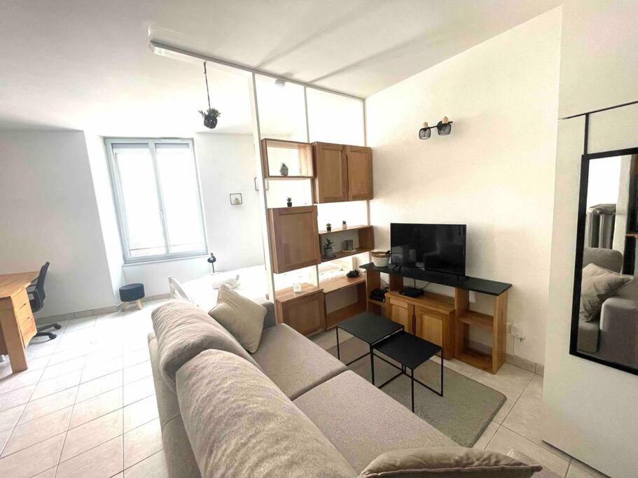 a living room with a couch and a desk with a television at Studio à 1 mn de la gare viotte (rue de Belfort) in Besançon