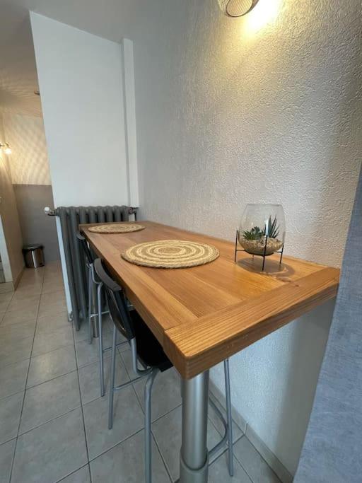 a wooden table with a wine glass on top of it at Studio à 1 mn de la gare viotte (rue de Belfort) in Besançon