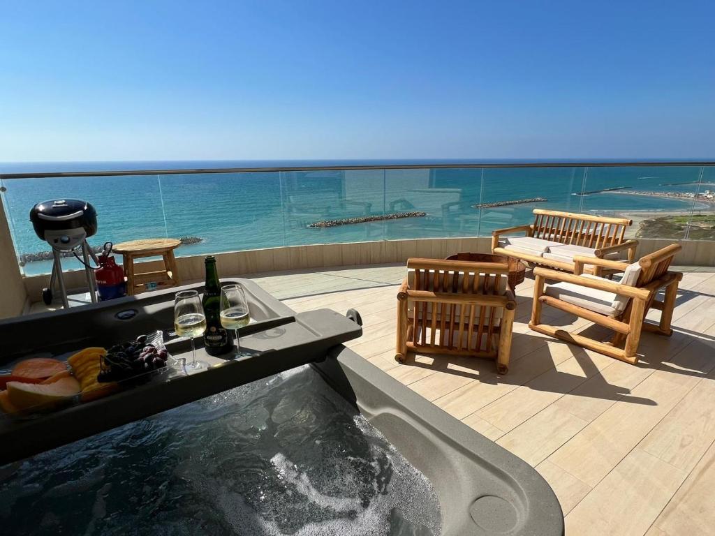 a hot tub on a balcony with a view of the ocean at Shamyam -שמיים- דירות מהממות על חוף הים עם ג'קוזי פרטי ובריכה במתחם in Netanya