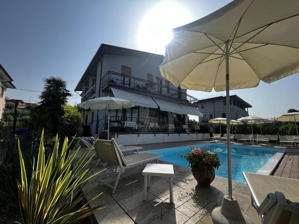 a pool with a chair and an umbrella next to a building at Hotel Renata in Lazise