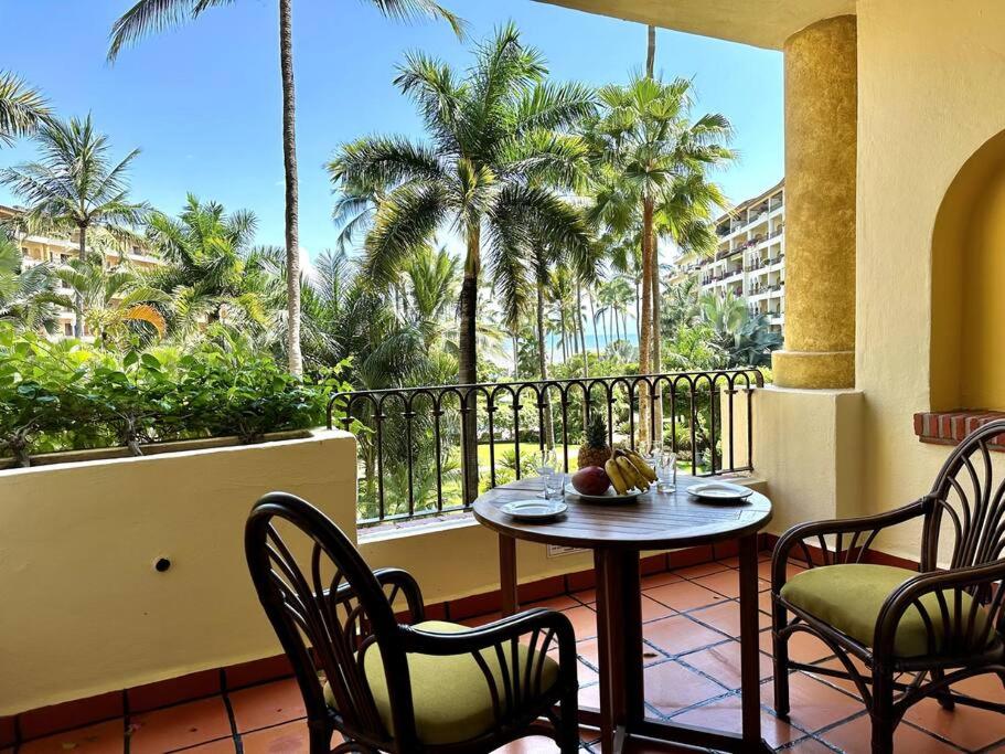 d'une table et de chaises sur un balcon avec des palmiers. dans l'établissement Departamento Frente a la Playa, Velas Vallarta, à Puerto Vallarta