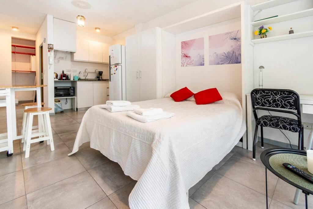 Espacio c/ Patio privado, lavadora y TV Premium في بوينس آيرس: غرفة نوم عليها سرير ومخدات حمراء